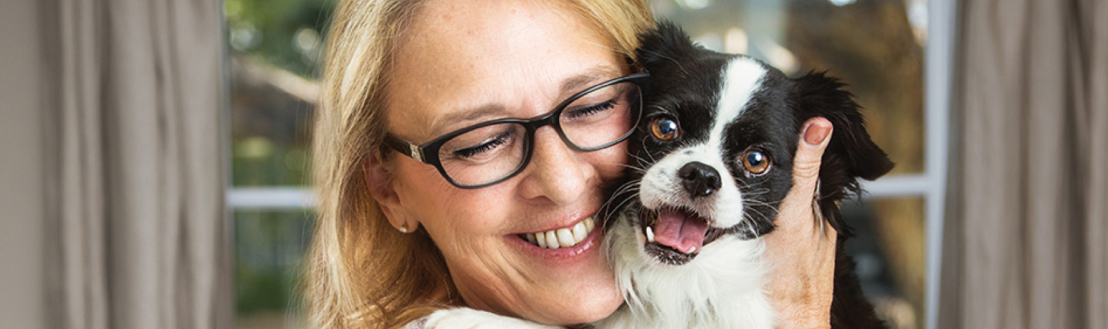 A middle aged woman holds her dog close showing affection for her pet